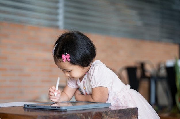 Une petite fille écrit sur une tablette