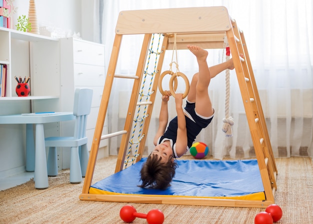 Petite fille effectue des exercices de gymnastique sur un complexe sportif en bois