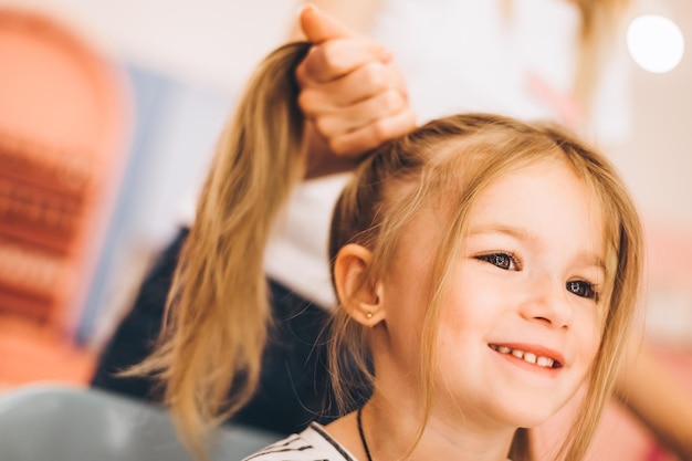 Photo petite fille élégante dans un salon de beauté pour enfants où elle a fait une belle coiffure