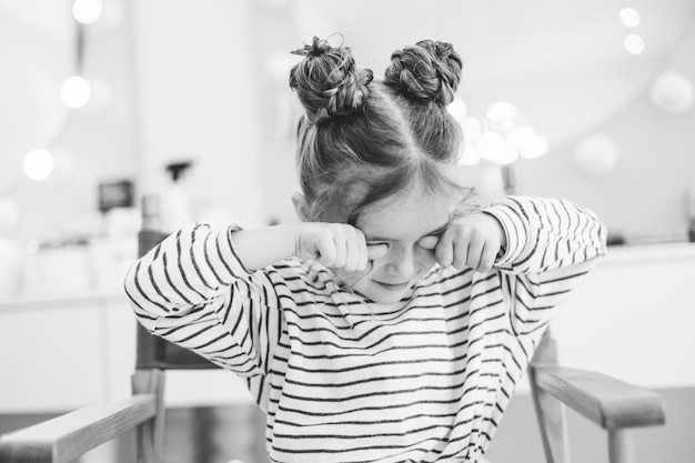 Petite fille élégante dans un salon de beauté pour enfants où elle a fait une belle coiffure