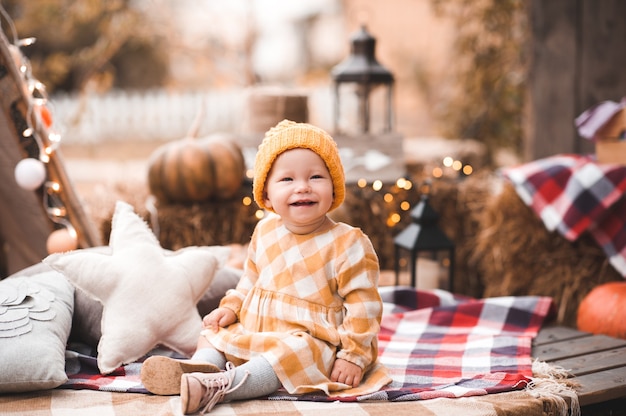 Petite fille élégante portant des vêtements d'automne posant avec des citrouilles à l'extérieur