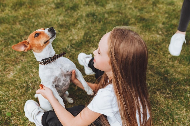 Une petite fille embrasse et étreint son chien terrier Jack Russell dans le parc L'amour entre le propriétaire et le chien un enfant tient un chien dans ses bras