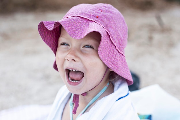 Petite fille enfant au panama criant assis sur la plage