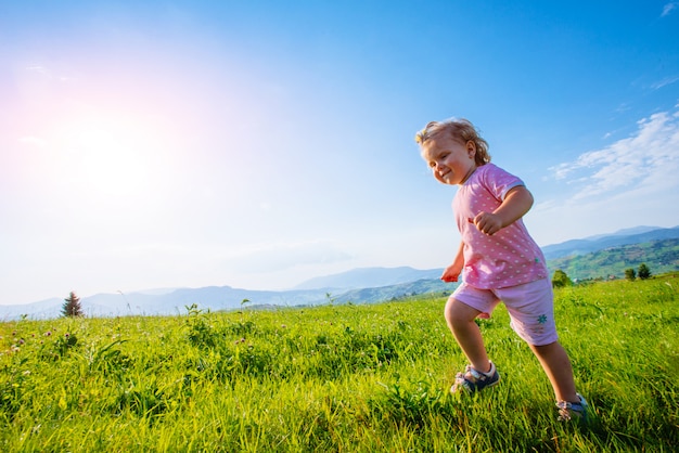 Petite fille enfant en bas âge en cours d'exécution dans un beau champ