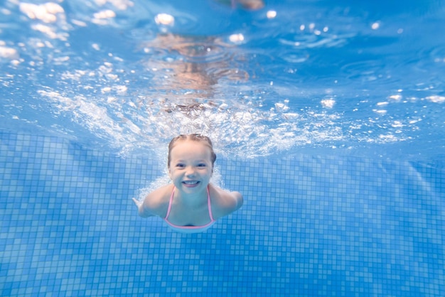 Petite fille enfant nageant sous l'eau dans la pataugeoire Plongée Apprentissage bébé enfant à nager Profitez de la natation et des bulles