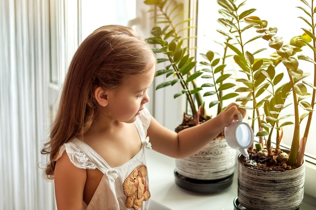 petite fille enfant prend soin des plantes de la maison