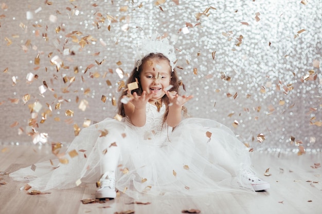 Petite fille enfant en robe de princesse sur fond de confettis