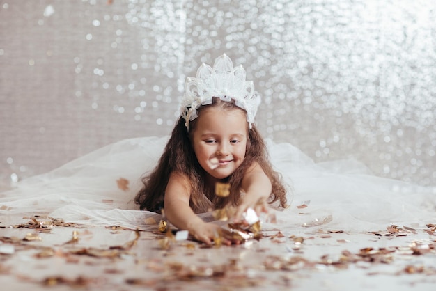 Petite fille enfant en robe de princesse sur fond de confettis