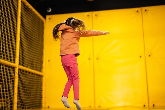 Petite fille enfant sautant sur un trampoline au parc de jeux jaune