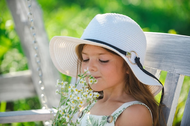 Petite fille enfant sent des fleurs sur l'arrière-cour verte Adorable enfant sur un pré d'été et sent des fleurs Amusement d'été pour la famille avec des enfants à l'extérieur dans un beau jardin de printemps