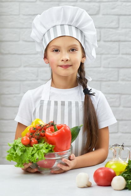Petite fille enfant tenant un bol de légumes frais