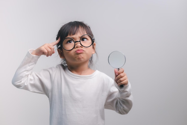 Petite fille enfant tenant une loupe sur fond blanc