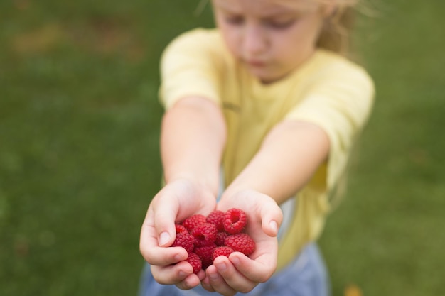 Petite fille enfant tenant une poignée de baies rougesframboises