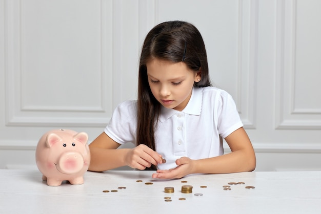 Petite fille enfant avec tirelire à la maison