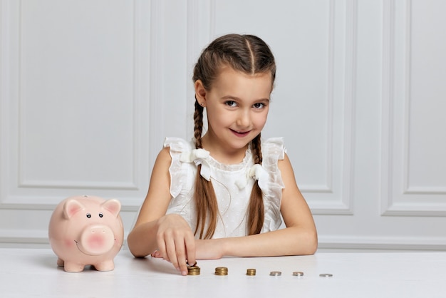 Petite fille enfant avec tirelire à la maison