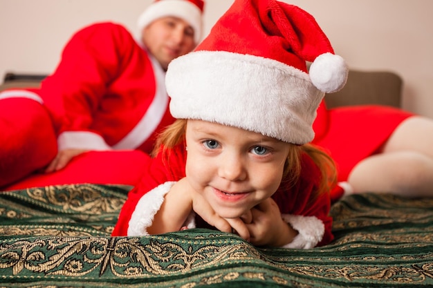 Petite fille espiègle en bonnet de Noel profitant de Noël avec ses parents à la maison Joyeux Noël et Nouvel An