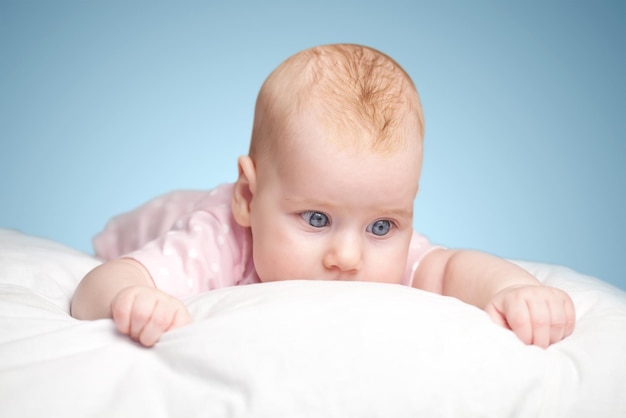 La petite fille est allongée sur un oreiller - nuage. sur fond bleu