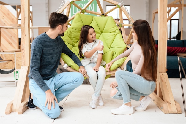 Une petite fille est assise sur une balançoire.