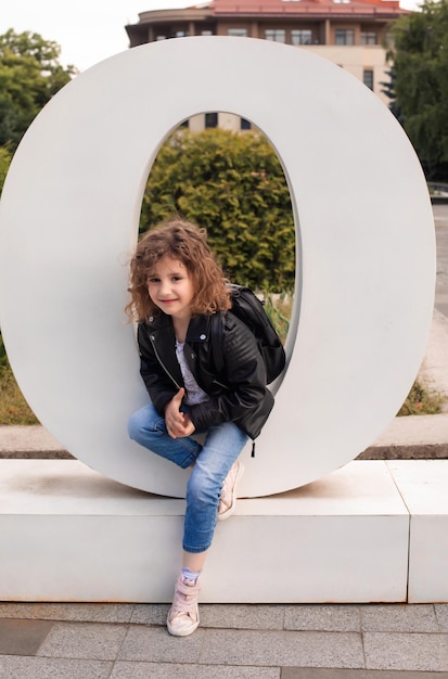 La petite fille est assise dans la grande lettre de la ville