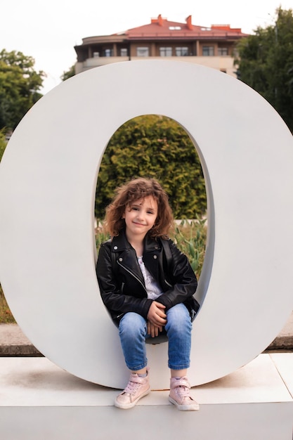 La petite fille est assise dans la grande lettre de la ville