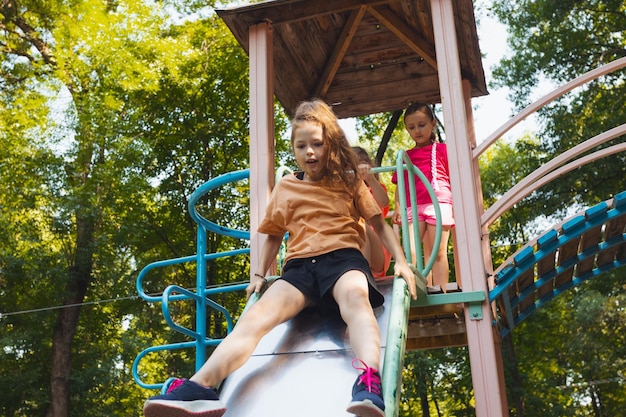 La petite fille est assise sur un toboggan dans l'aire de jeux