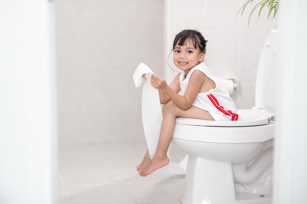 La petite fille est assise sur les toilettes souffrant de constipation ou d'hémorroïdes