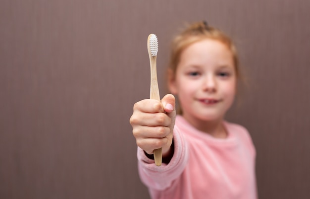 Petite fille est titulaire d'une brosse à dents écologique