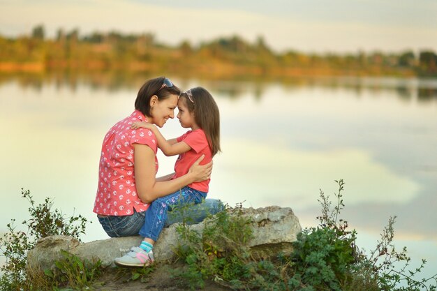 Petite fille étreignant sa mère près du lac