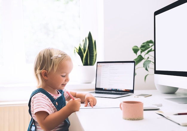 Petite fille étudiant et dessinant au bureau Apprentissage en ligne pour enfants