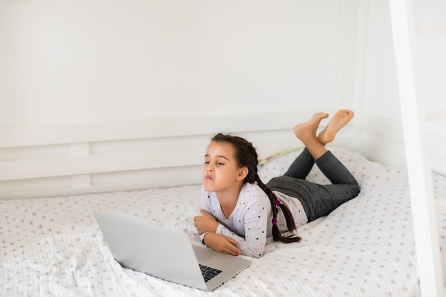 Petite fille étudiant en ligne à l'aide de son ordinateur portable à la maison