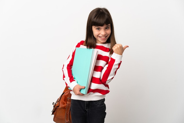 Petite fille étudiante isolée sur un mur blanc pointant vers le côté pour présenter un produit