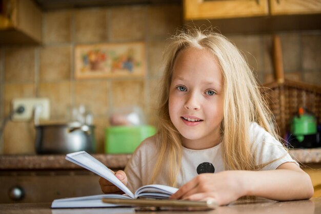 Petite fille étudiante lisant un livre à la maison