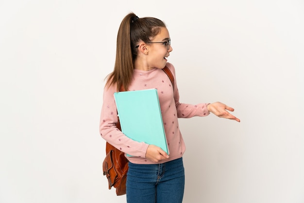 Petite fille étudiante sur un mur isolé avec une expression de surprise tout en regardant côté