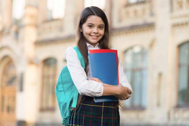 Petite fille étudiante uniforme scolaire et sac à dos tenir des livres concept d'éducation formelle