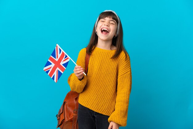 Petite fille étudie l'anglais isolé sur un mur bleu en riant