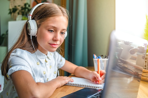 Une petite fille étudie à la maison à l'aide d'un ordinateur portable