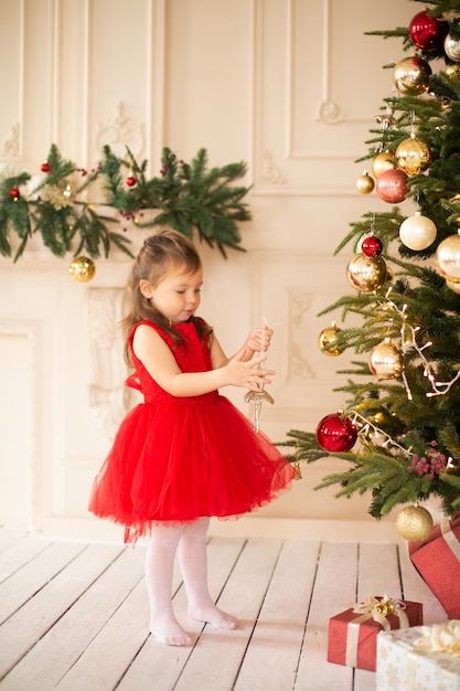 Petite fille excitée pour les vacances de Noël avec tous ces cadeaux et décoration de conte de fées.