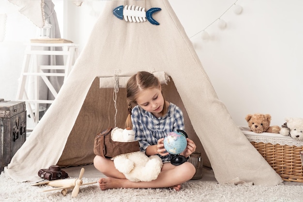 Petite fille explorant le globe avec un ours en peluche