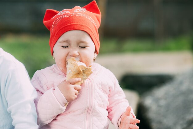 Petite fille à l'extérieur dans le village de manger de la crème glacée très goulûment