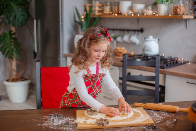 Petite fille faisant des biscuits pour Noël dans la cuisine