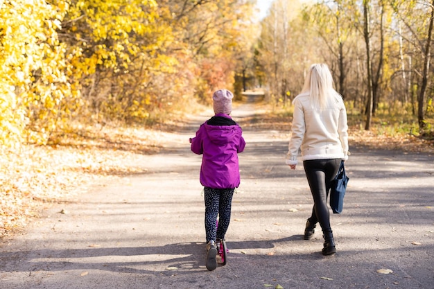 petite fille faisant du scooter à l'école avec sa mère.