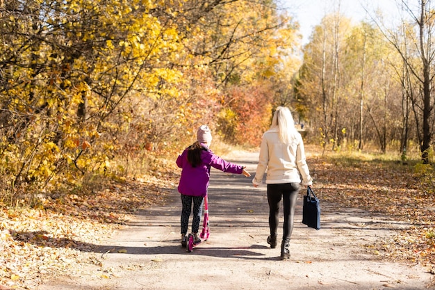 Petite fille faisant du scooter à l'école avec sa mère