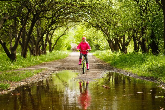 Petite fille faisant du vélo dans une flaque d'eau