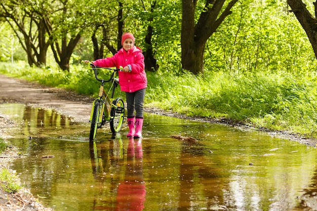 Petite fille faisant du vélo dans une flaque d'eau