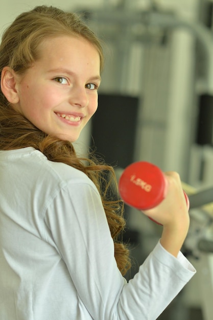 Petite fille faisant des exercices avec haltère dans la salle de gym