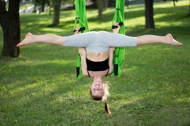 Petite fille faisant des exercices de yoga avec un hamac dans le parc