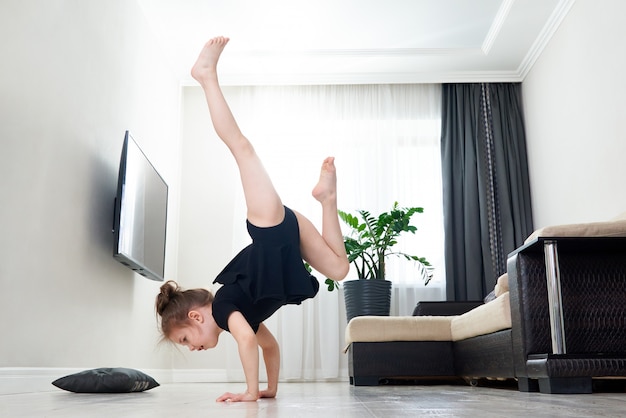 Petite fille faisant de la gymnastique à la maison debout sur ses mains à l'envers