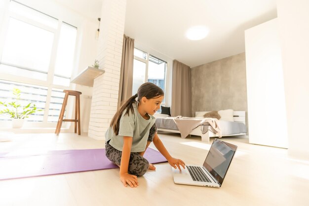 Petite fille faisant ses devoirs à la maison et utilisant un ordinateur portable