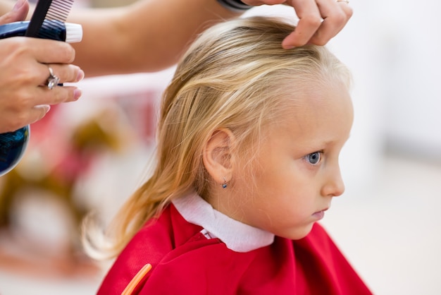 Une petite fille fait une coupe de cheveux.