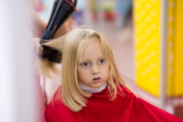 Une petite fille fait une coupe de cheveux.